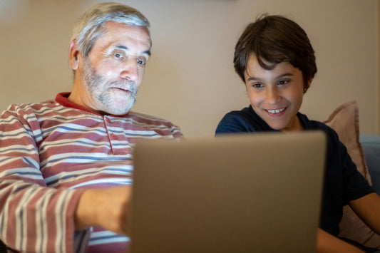 A happy grandchild waving at their grandparent during a video call on a tablet.