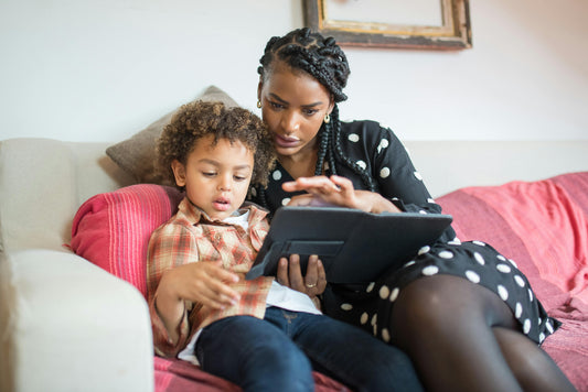 A mother and her child laughing together while enjoying a digital gift on their tablet.