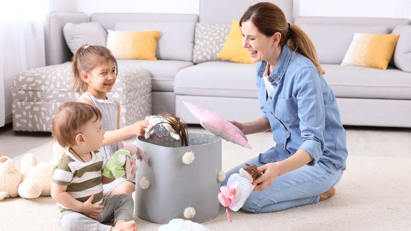 A parent and child happily organizing toys into a storage box for a toy rotation system.